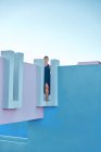 Mulher de pé no topo do edifício azul e olhando para longe — Fotografia de Stock