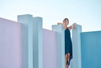 Mujer de pie sobre el edificio azul y mirando a la cámara - foto de stock