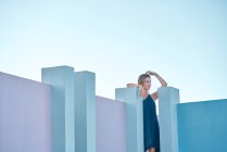 Frau steht auf blauem Gebäude und blickt in Kamera — Stockfoto