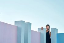 Woman standing on top of blue building and talking by smartphone — Stock Photo