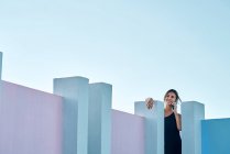 Frau steht auf blauem Gebäude und spricht per Smartphone — Stockfoto