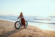 Joyeuse femme à vélo le long de la plage paisible — Photo de stock
