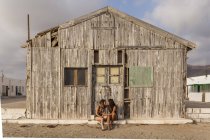 Ласковая женская пара сидит у старого деревянного сарая, держа руки и касаясь лбами — стоковое фото