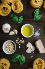 Vue en haut des herbes fraîches et du fromage avec huile et pâtes tagliatelle disposées sur table rustique en bois — Photo de stock
