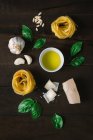 Vista superior de ervas frescas e queijo com óleo e massa tagliatelle dispostos na mesa de madeira rústica — Fotografia de Stock