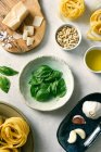 Basilikumblätter und Zutaten für Pesto-Sauce auf Tellern auf dem Tisch — Stockfoto
