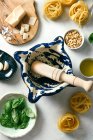 Pestle and mortar with ingredients for pesto sauce, top view — Stock Photo