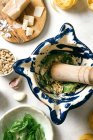 Pestle and mortar with ingredients for pesto sauce on table — Stock Photo