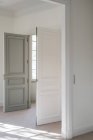 Open bicolor swing door with modern handle in white minimalistic interior - foto de stock