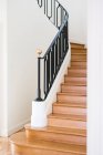 Escalier en bois massif avec rampe noire dans la maison avec intérieur léger — Photo de stock