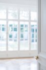 Offene weiße Tür mit goldenem Griff in leicht minimalistischem Interieur auf unscharfem Hintergrund — Stockfoto