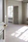 Open white door with golden handle in light minimalist interior on blurred background — Stock Photo