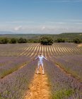 Aufgeregter Mann steht mit ausgestreckten Händen auf dem Weg zwischen blühenden Lavendelreihen und blickt auf einen sonnigen Tag — Stockfoto