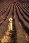 Frau mit ausgestreckten Armen steht im Lavendelfeld — Stockfoto