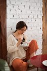 Friedliche Frau trinkt Kaffee, während sie sich zu Hause ausruht — Stockfoto