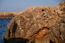 Child climbing cliffs on seashore — Stock Photo