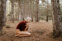 Hermosa mujer moderna descansando descalza en el bosque siempreverde - foto de stock