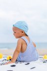 Baby mit Mütze am Strand neben seinen Gummienten — Stockfoto