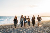 Eine Gruppe junger Leute am Strand rennt in die Kamera, während sie Papiere in der Hand hält — Stockfoto