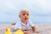 Portrait of baby boy playing with rubber ducks on the beach — Stock Photo