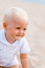 Portrait of a blonde baby smiling on the beach — Stock Photo