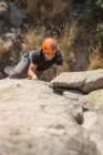 Зверху людина піднімається на скелю в природі з обладнанням для скелелазіння — стокове фото