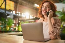 Junge Frau telefoniert während der Arbeit am Laptop — Stockfoto
