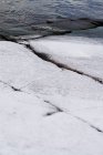 Primer plano de la superficie de roca procesada con grietas y arañazos cubiertos de nieve - foto de stock