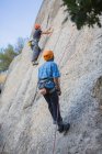 Aventuriers escalade montagne port harnais de sécurité contre paysage pittoresque — Photo de stock