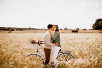 Verliebte posieren mit dem Fahrrad auf Roggenfeld — Stockfoto