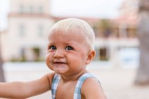 Portrait of a blonde baby smiling on the beach — Stock Photo