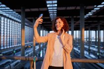 Sorrindo jovem mulher tomando selfie na estação — Fotografia de Stock