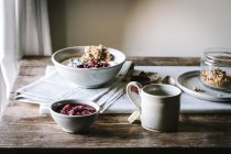 Delicious breakfast bowl with berries, quinoa, rice and groats near tea cup and newspaper — Stock Photo