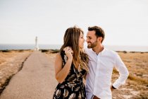 Smiling lovers cuddling on path to sea — Stock Photo