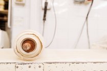 Лист тонкого теста, обмотанный деревянной скалкой на выветриваемом столе в пекарне — стоковое фото