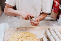 From anonymous confectioner putting fresh soft dough in small cup over table in bakery kitchen — Stock Photo