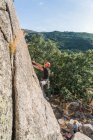 Homem escalando uma rocha na natureza com equipamento de escalada — Fotografia de Stock