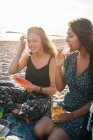 Dos mujeres pensativas en la playa comiendo sandía - foto de stock