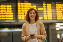 Рыжая молодая женщина с помощью смартфона на станции — стоковое фото