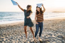 Two beautiful women dancing on the beach, a girl with brown hair and a girl with Asian features — Stock Photo