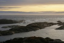 Гладенькі валуни на порожньому узбережжі з морськими хвилями під темним вечірнім небом у Норвегії. — стокове фото