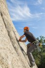Homem escalando uma rocha na natureza com equipamento de escalada — Fotografia de Stock