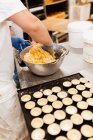 Zuckerbäcker in Handschuhen und gleichmäßigem Mischen und Kneten von weichem, frischem Teig während der Zubereitung von Gebäck in der Bäckerei — Stockfoto
