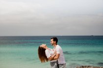 Gli amanti ridenti che si abbracciano sulla spiaggia — Foto stock