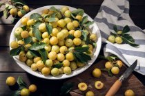 Fruta de mirabela de ameixa amarela fresca na tigela na mesa de madeira — Fotografia de Stock