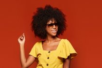 Africana donna americana posa sorridendo a macchina fotografica su sfondo rosso brillante — Foto stock