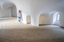 Mulher casual inclinada na parede em galeria espaçosa com janelas — Fotografia de Stock