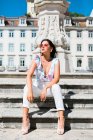 Rilassato bella donna in abito alla moda seduto su una scala in pietra su strada panoramica — Foto stock
