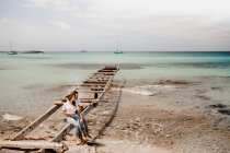 Amoureux heureux assis sur jetée détruite sur le bord de la mer — Photo de stock