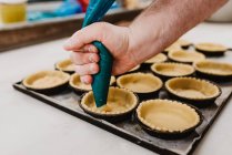Anonymous cook squeezing fresh pastry dough on tray with paper — Stock Photo